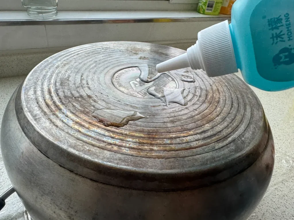 Applying blue cleaning gel to a stained stainless steel pot bottom
