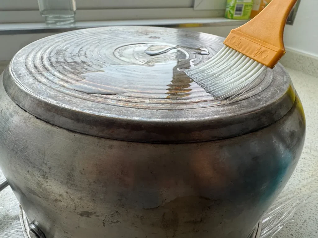 Brushing cleaning gel across a stained stainless steel pot bottom