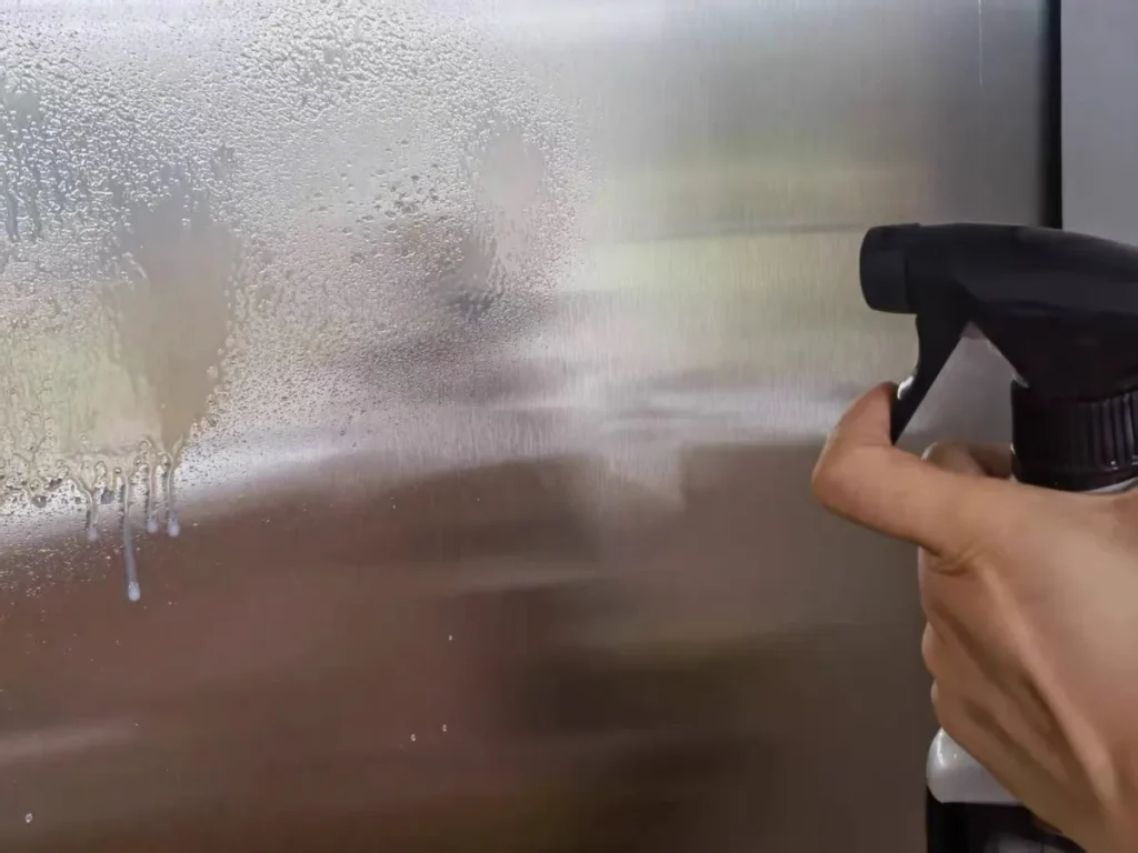 Spraying Weiman Stainless Steel Cleaner on a stainless steel refrigerator