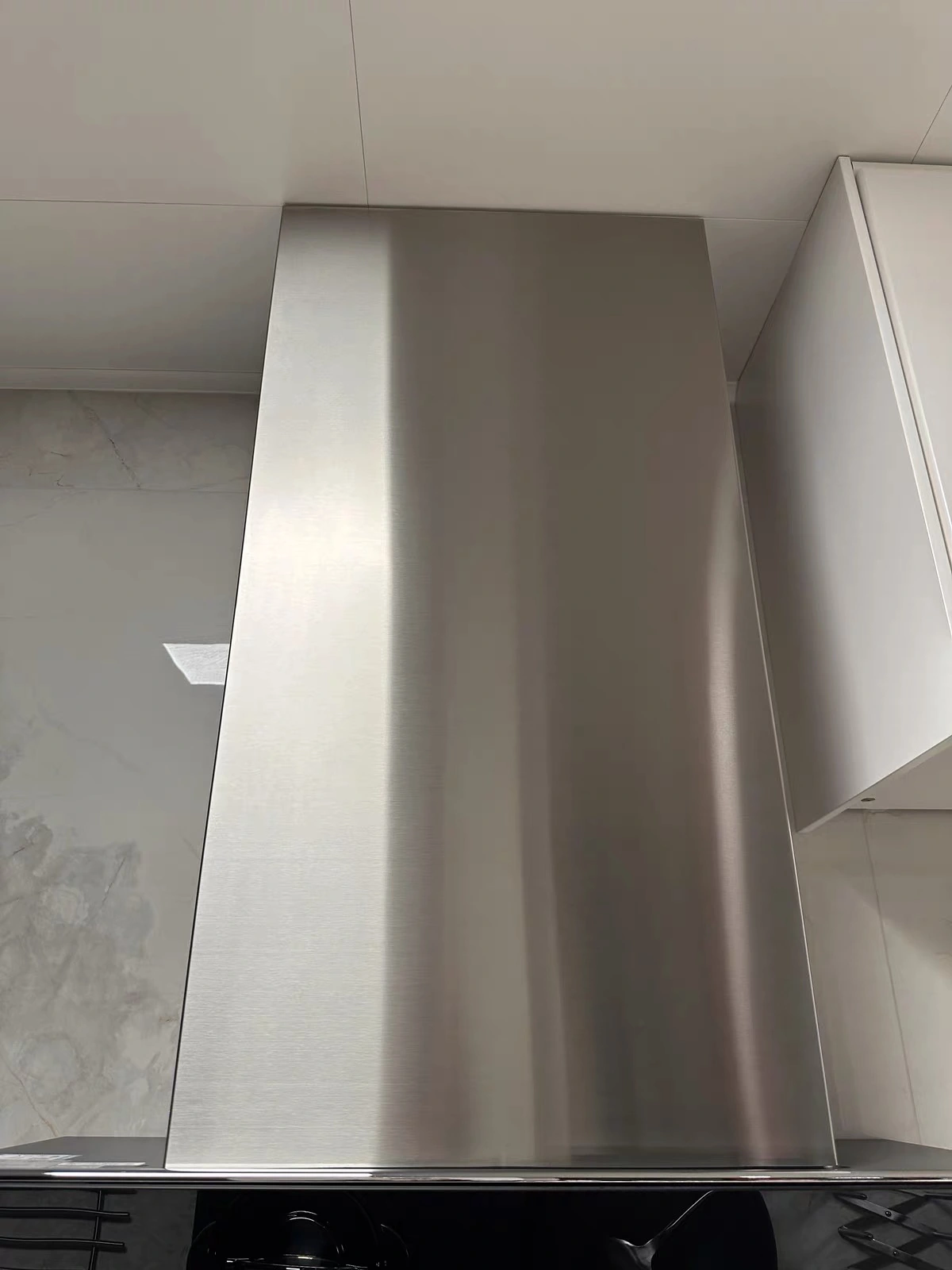 Close-up of a brushed stainless steel range hood showing the direction of the grain