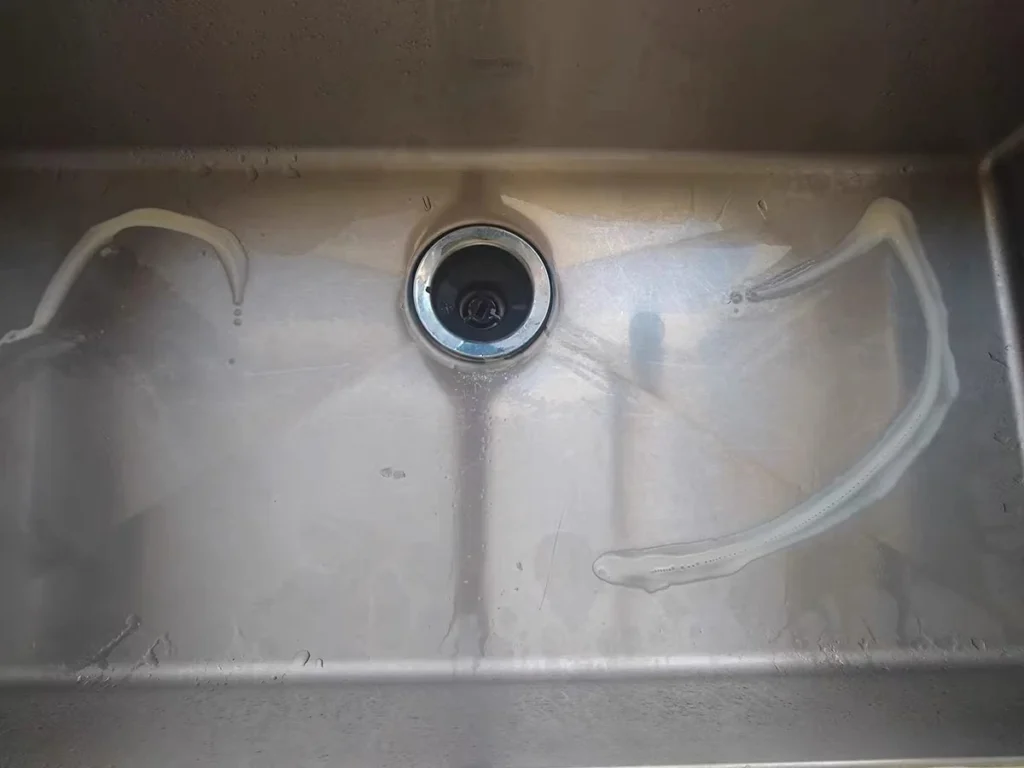 Stainless steel sink before cleaning with visible dullness and residue