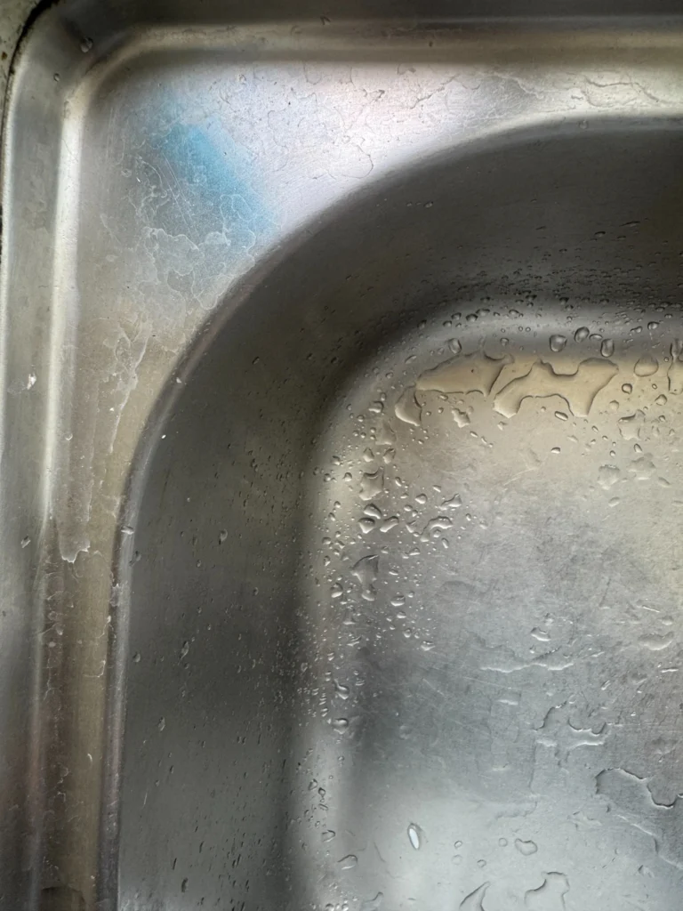 White water spots and mineral buildup on a stainless steel sink