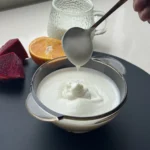 A spoonful of smooth homemade plain yogurt in a glass bowl