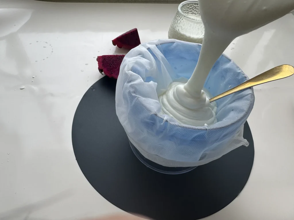 Homemade yogurt being poured into a lined strainer