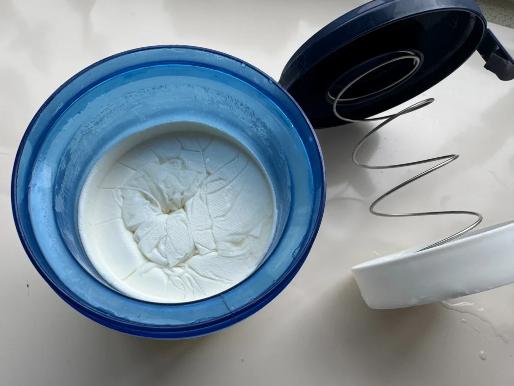 Thick homemade yogurt remaining in a yogurt strainer after whey has drained away
