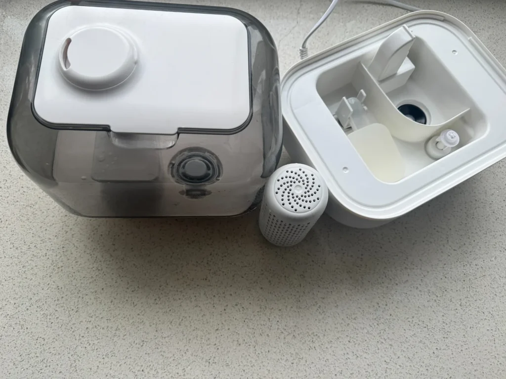 Disassembled humidifier with water tank, base, and filter ready for cleaning