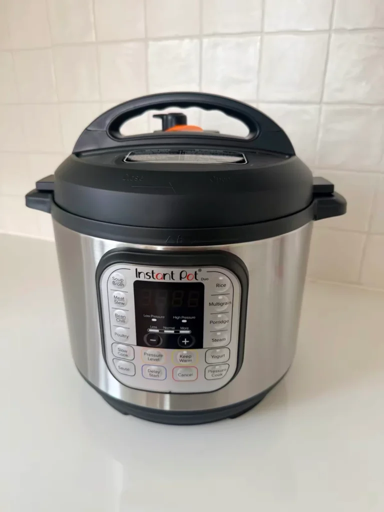 A stainless steel electric pressure cooker with a Yogurt button on the front control panel.