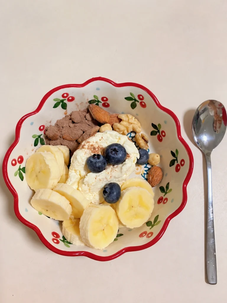 Yogurt bowl topped with banana slices, blueberries, almonds, and walnuts