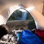 Camping sleep setup inside a tent near a waterfall
