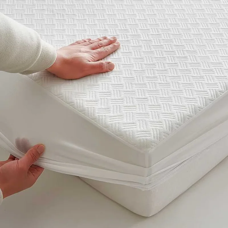 Hands fitting a white mattress protector around the corner of a mattress