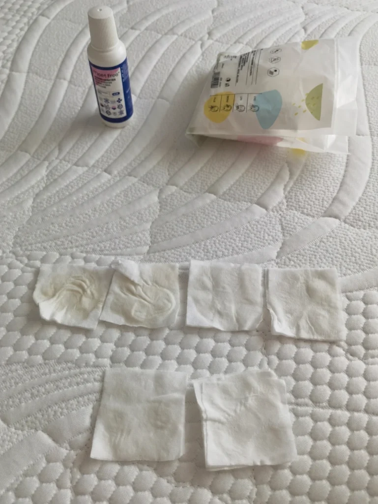 Small pieces of tissue, a bottle, and a packet arranged on a white quilted mattress