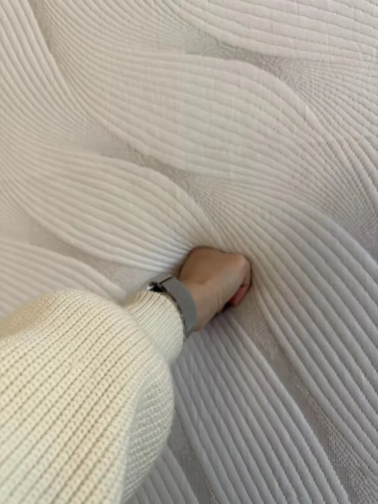 Hand pressing into a memory foam mattress to show how the surface responds to pressure