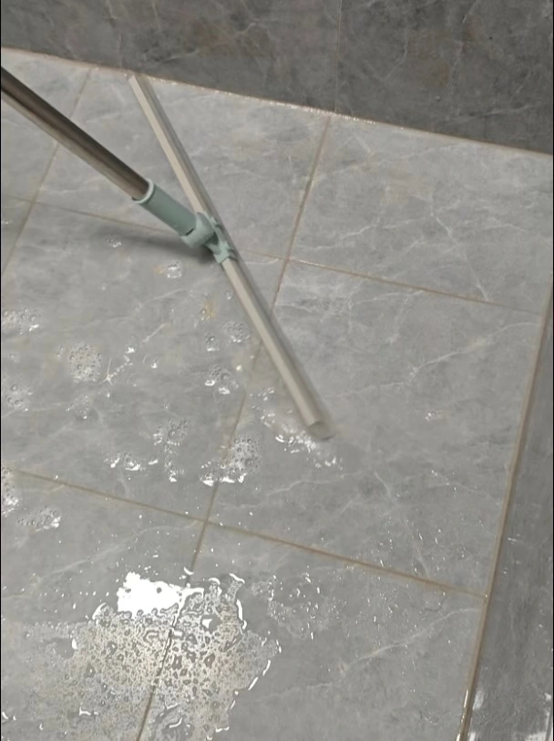 Removing standing water from shower floor tiles with a squeegee