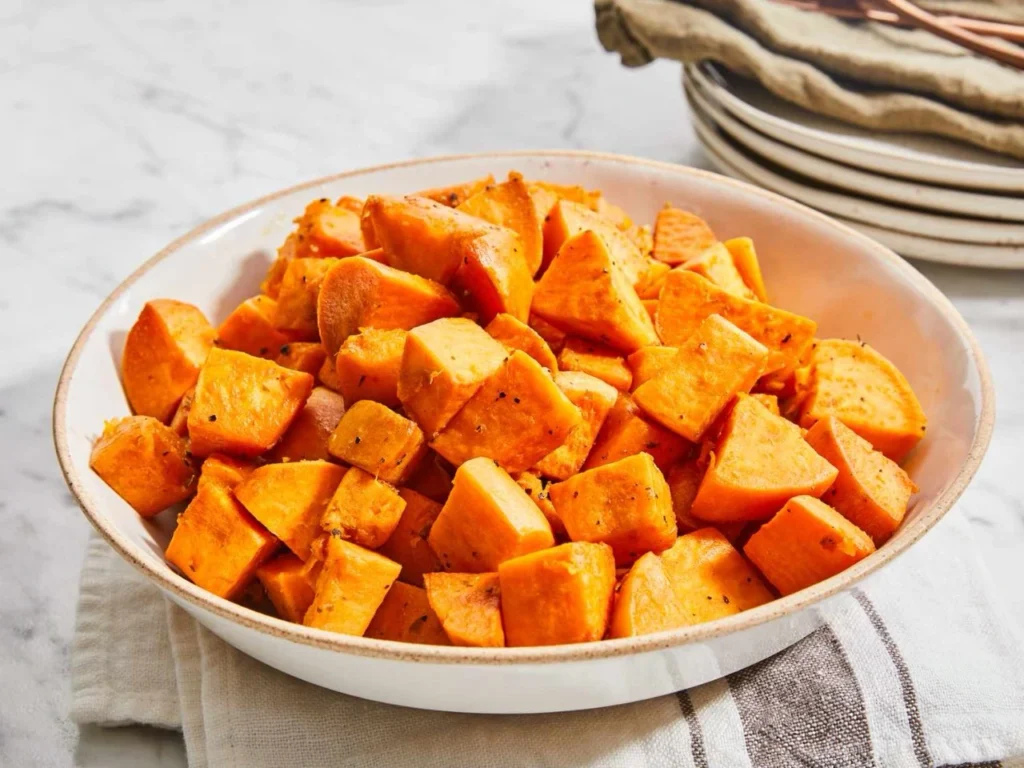 Golden roasted sweet potato cubes served in a white bowl.
