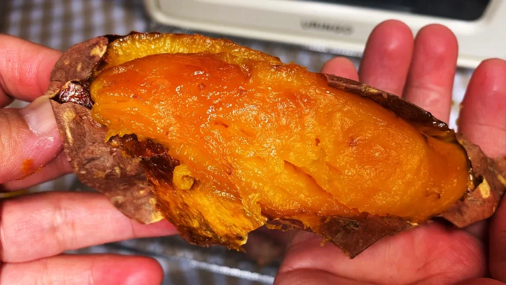 Sweet potatoes in air fryer, baked whole and split open to show their soft orange flesh.